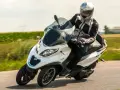 Biały Piaggio MP3 500 z kierowcą w kasku pędzi po drodze. Zastanawiasz się nad jego spalaniem?