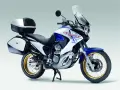 Honda Transalp 700 dane techniczne: turystyczny motocykl z kuframi, biało-niebieski, złote felgi, gotowy na przygodę.