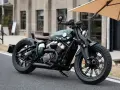 Stylowy, zielony motocykl typu cruiser z brązowym siedzeniem. Idealny do miejskich podróży, mógłby znaleźć się w rankingu motocykli cruiser.