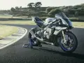 Srebrno-niebieski motocykl Yamaha R1M na torze wyścigowym, gotowy do jazdy.