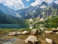 Kamienista droga na Morskie Oko prowadzi przez malownicze Tatry. Jezioro odbija skaliste szczyty i zielone lasy.