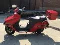 Czerwony skuter Honda Spacy 250 z kufrem, gotowy do podróży.