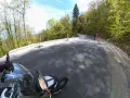 Motocyklista pokonuje zakręty na malowniczej drodze stu zakrętów, otoczonej zielonymi lasami.
