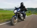 Motocykle szosowo turystyczne przemierzają malownicze, zielone wzgórza.