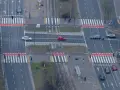 Skrzyżowanie z tramwajami i pasami. Czerwony samochód wykonuje wyprzedzanie na pasach, ryzykując kolizję z pieszymi.