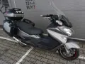 Srebrny Suzuki Burgman 650 Executive z kuframi, gotowy na dalekie podróże.