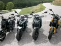 Cztery motocykle typu naked stojące na zakręcie górskiej drogi.