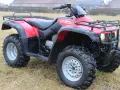 Czerwony quad Honda TRX 350 Foreman gotowy do jazdy po nierównym terenie.