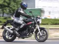 Motocyklista w kasku i kombinezonie jedzie na czarnym motocyklu Hyosung GT 125.
