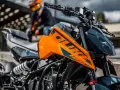 Pomarańczowy KTM Duke 390, zarejestrowany na 125, z motocyklistą w tle. Gotowy na przygodę!