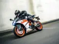 Motocyklista w kasku śmiga na KTM RC 125, osiągając maksymalną prędkość na torze.
