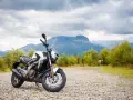 Biało-czarny Bajaj Dominar 400 na tle gór i chmur. Gotowy na przygodę w dziczy.