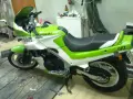 Zielono-biały motocykl Kawasaki GPZ 500 z napisem "GPZ" na tyle. Stoi na drewnianej podłodze w garażu.