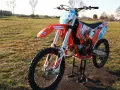 Pomarańczowy motocykl KTM SX 125 na stojaku, gotowy do jazdy. Zastanawiasz się, ile koni ma KTM SX 125? Ten model to potęga na torze!