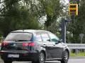 Czarny samochód mija fotoradar. Kierowca motocykla powinien uważać na ograniczenie prędkości.