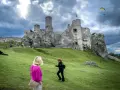 Ruiny zamku na skale, część Szlaku Orlich Gniazd. Na pierwszym planie dwie kobiety, w tle paralotniarz.