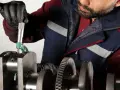 Mechanik mierzy wał korbowy, sprawdzając, czy nie ma uszkodzonej panewki.