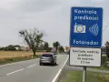 Znak "Kontrola prędkości Fotoradar" informuje, że czy fotoradar musi być oznakowany. Obok droga i pola.