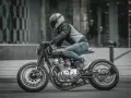 Motocyklista w kasku i jeansach pędzi na stylowym Suzuki GS 650 po miejskiej ulicy.