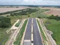Budowa drogi ekspresowej S2 Siedlce-Biała Podlaska. Nowa nawierzchnia asfaltowa w otoczeniu zieleni i pól.
