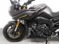 Ciemnoszary motocykl Yamaha FZ8 z żółtym napisem "FAZER" na baku. Widoczny fragment przedniego koła, zawieszenia i silnika.