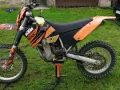 Pomarańczowy motocykl KTM 400 EXC na stojaku, gotowy do jazdy po bezdrożach.