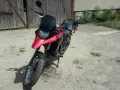 Czerwony motocykl Derbi Terra 125 stoi przed drewnianą stodołą.