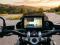 Nawigacja na motocyklu z Google Maps w trybie motocyklowym. Widok na zakręconą drogę w górach o zachodzie słońca.