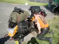 Motocyklista sprawdza uszkodzony gaźnik objawy. Na motocyklu sakwy, zielony worek i czarne rękawice.