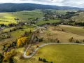 Malownicza autostrada sudecka wijąca się przez jesienne krajobrazy, pola i lasy. W oddali widać zabudowania wsi.