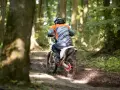 Motocyklista w kasku i kolorowej bluzie pędzi leśnym szlakiem. Od ilu lat można jeździć crossem? Odpowiedź zależy od przepisów i umiejętności.
