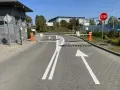 Przed wjazdem na teren, gdzie obowiązuje znak P-15, stoją szlabany. Na drodze namalowano strzałki kierunkowe i napis STOP.