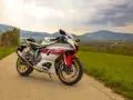 Sportowy motocykl Yamaha R7 w białym malowaniu z czerwonymi akcentami, zaparkowany na drodze wśród zielonych wzgórz. Sprawdź aktualną yamaha r7 cena!