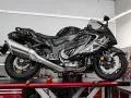 Czarny motocykl na podnośniku, gotowy do serwisu. Widać duży, chromowany wydech, który odcina się od reszty maszyny.