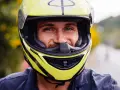 Uśmiechnięty mężczyzna w żółtym kasku motocyklowym.