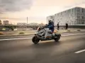 Mężczyzna w kasku jedzie na skuterze BMW CE 04 po mieście.