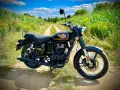 Czarny motocykl Royal Enfield Diesel na polnej drodze, otoczony zielenią i kukurydzą.