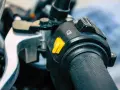 Pomarańczowy przycisk na kierownicy motocykla, który może służyć jako kill switch, obok przełącznika świateł.