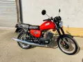 Czerwony motocykl MZ ETZ 251 z lat 80. stoi przed garażem.