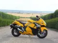 Żółty Suzuki Hayabusa na tle pól i zielonych żywopłotów. Sprawdź aktualną suzuki hayabusa cena!