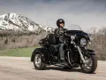 Mężczyzna w kasku i skórzanej kurtce jedzie czarnym motocyklem trójkołowym L5E. W tle góry ze śniegiem.