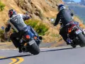 Dwóch motocyklistów na zakręcie. Jeden na Yamaha R3, drugi na V-Max, w skórzanych kombinezonach, pokonuje górską drogę.