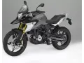 Szary motocykl BMW 310 GS z czarnym siedzeniem i złotymi amortyzatorami, gotowy na przygodę.