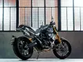 Czarny motor scrambler z podwójnym wydechem i złotym zawieszeniem, gotowy do jazdy po miejskich ulicach.