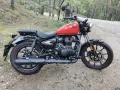 Czerwony Royal Enfield Meteor 350 na leśnej drodze. Klasyczny wygląd i gotowość do podróży.