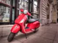 Czerwony skuter Vespa, idealny do miasta. Marzenie o posiadaniu go jest jak marzenie o zdobyciu prawa jazdy na skuter.
