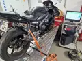 Czarny motocykl na hamowni, przygotowany do testów. Pomiar mocy i momentu obrotowego, czyli blokowanie motocykla na A2, to klucz do optymalizacji osiągów.