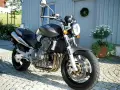 Szary motocykl Honda 919 zaparkowany na bruku przed domem.