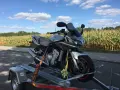 Srebrny motocykl Yamaha na przyczepce, gotowy do rejestracji z Niemiec. W tle pole kukurydzy i błękitne niebo z chmurami.
