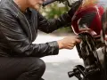 Kobieta w skórzanej kurtce sprawdza regulator napięcia w motocyklu.